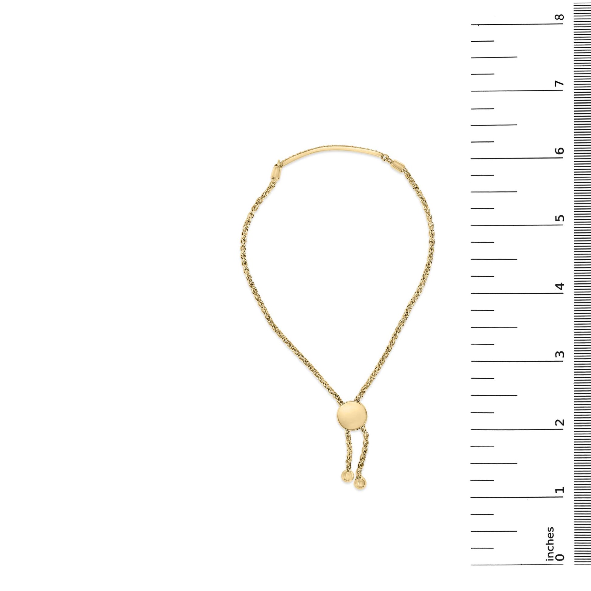 Yellow bracelet with a round centerpiece shown on a vertical ruler scale, top-down view.
