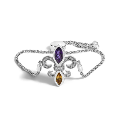 White metal bracelet with a fleur-de-lis centerpiece featuring white pave-set round gemstones, a purple marquise-shaped gemstone at the top, and an orange marquise-shaped gemstone at the bottom, shown from a front angle on a white background.