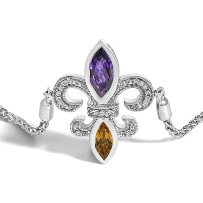 White metal bracelet with an ornate fleur-de-lis design featuring two marquise-shaped bezel-set purple and orange gemstones and multiple small pave-set white gemstones, shot from a front angle on a white background.