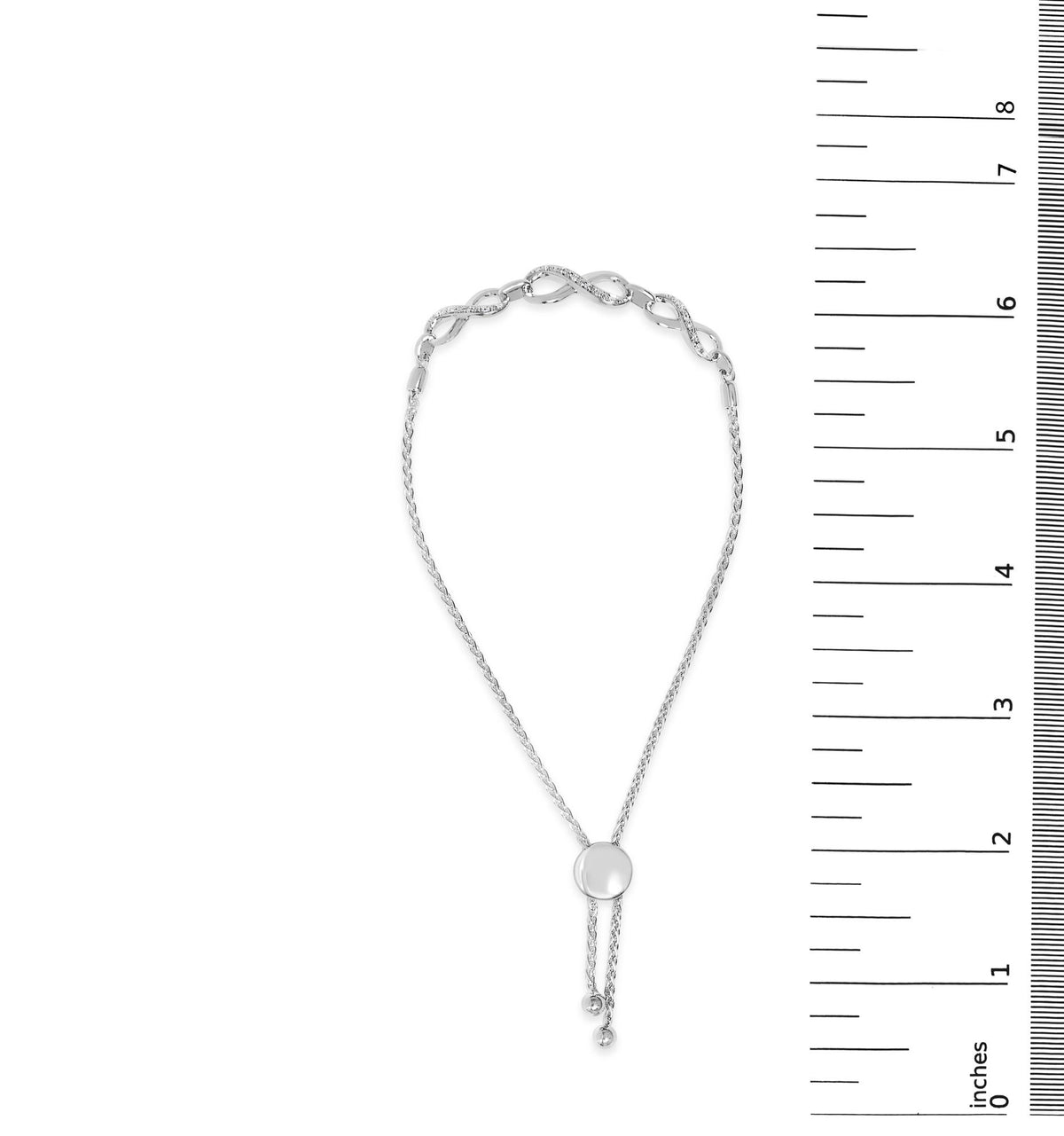 White bracelet with a round, pave-set white gemstones detail, shown on a scale, front view.