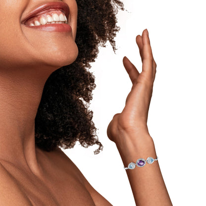 Bracelet with round white gemstones surrounding one oval purple gemstone and two pear-shaped blue gemstones, worn on a model's raised wrist, shot from a side angle.