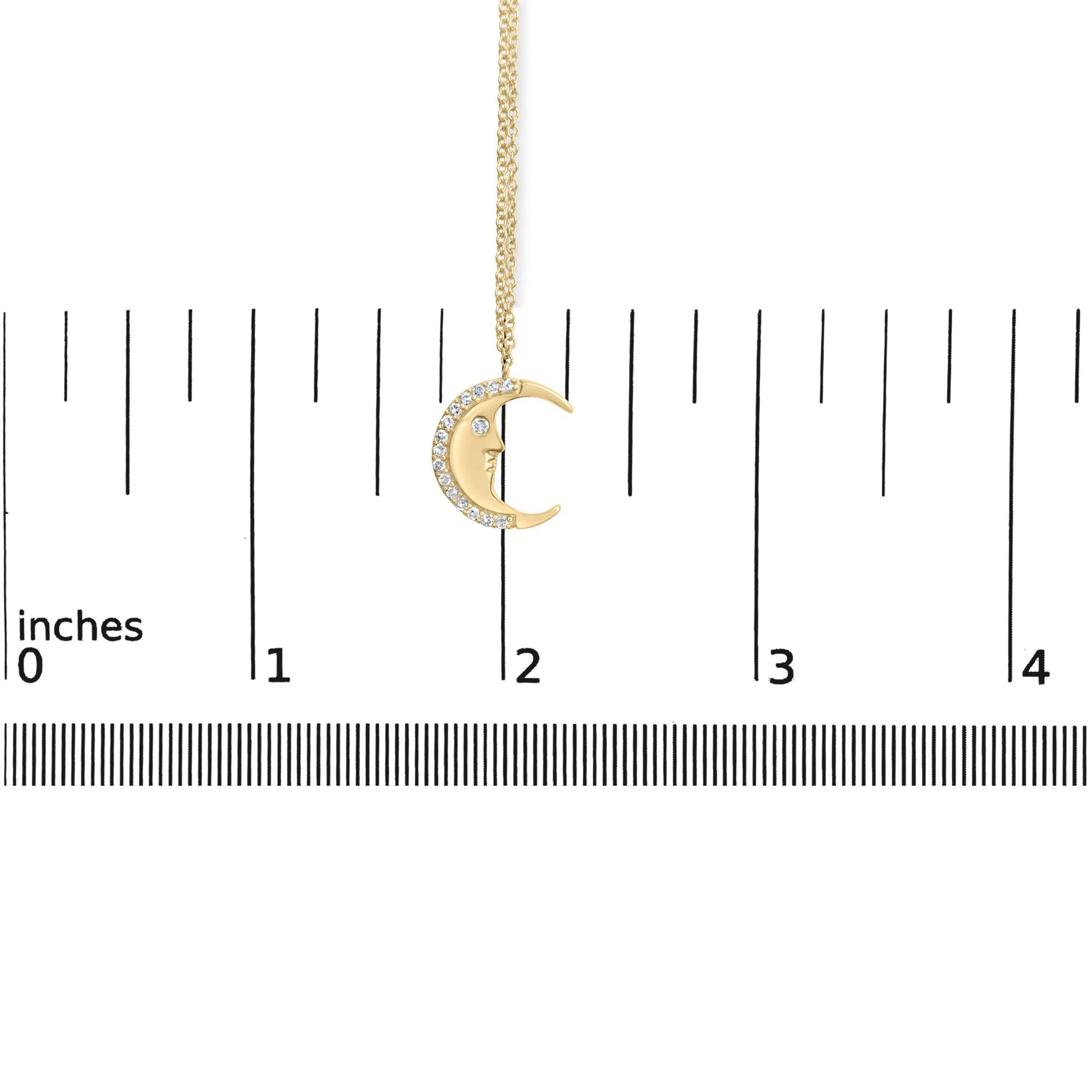 Yellow necklace with a crescent moon pendant featuring white round gemstones along the outer curve, shown hanging against a ruler for size reference, front-facing angle.