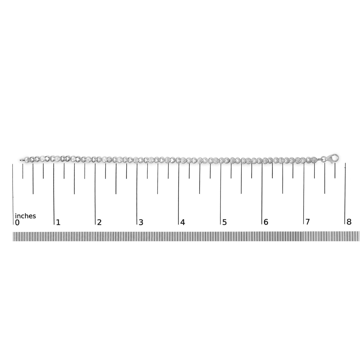 White bracelet with alternating smooth and pave-set heart-shaped links featuring white gemstones, shown laid flat on a ruler scale, shot from above.