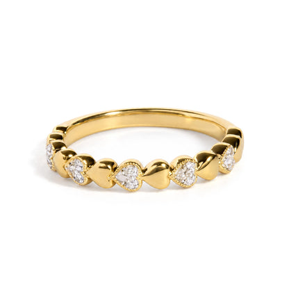 Close-up front angle of a yellow metal ring featuring a row of heart shapes, each containing white gemstones in a pave setting.