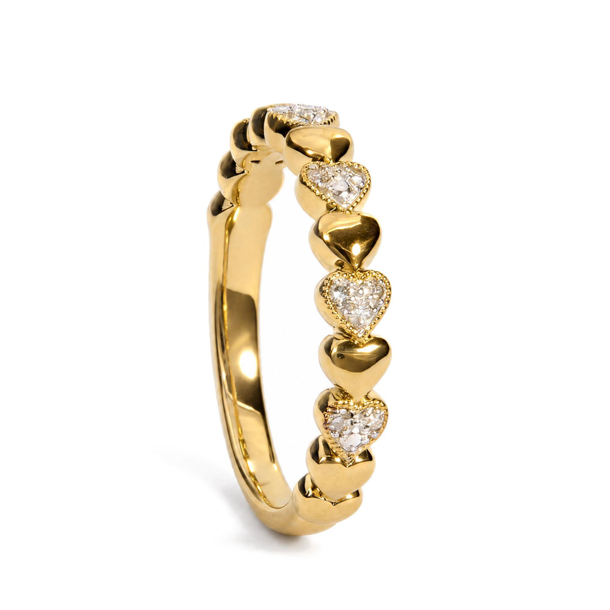 Close-up angled view of a yellow metal ring featuring alternating polished heart shapes and heart shapes with pave-set white gemstones.