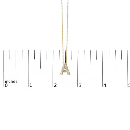 Close-up front view of a yellow metal necklace with a pendant shaped like the letter 'A,' adorned with white round gemstones in prong settings, shown on a scale.