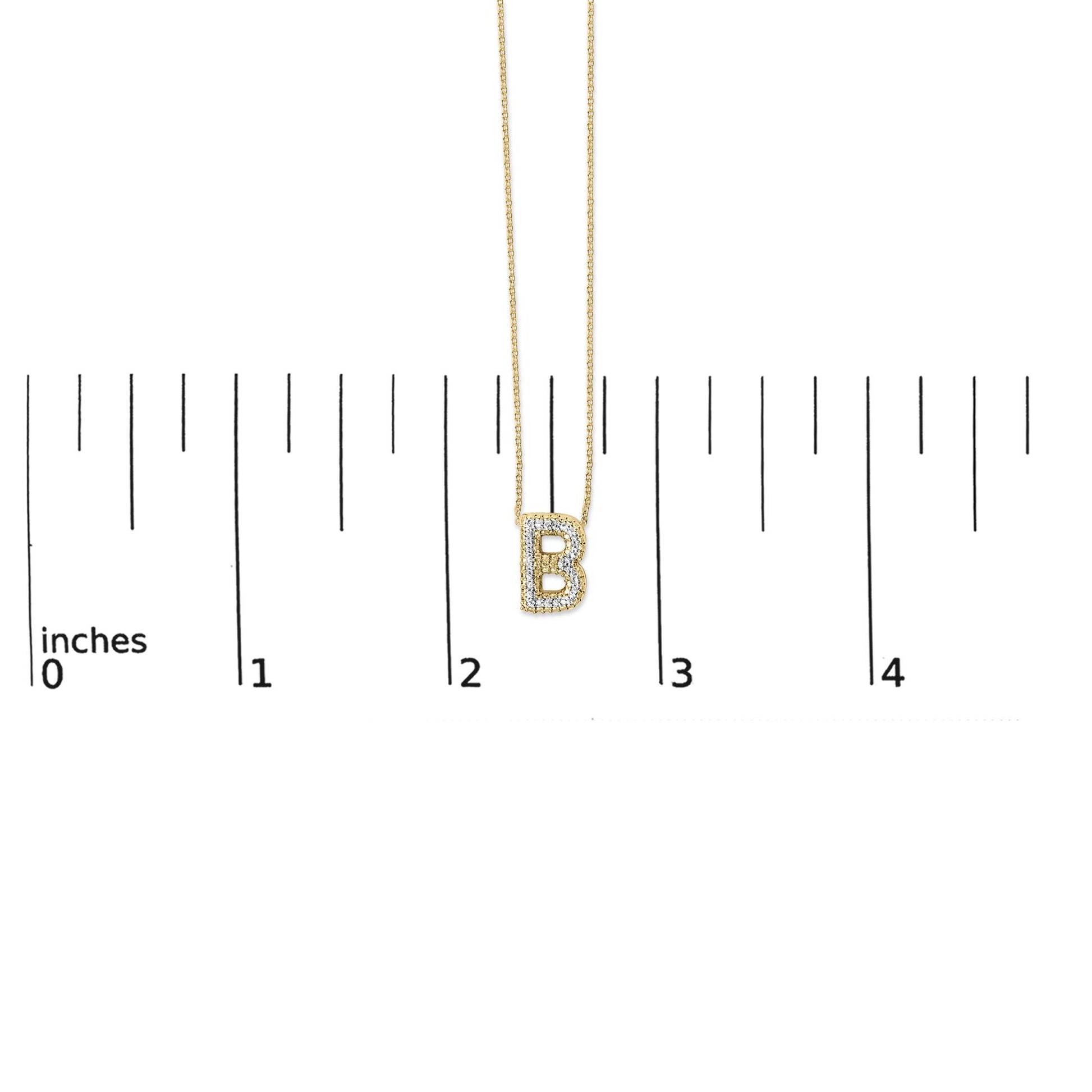 Close-up front view of a yellow necklace pendant shaped like the letter B, adorned with white gemstones in a prong setting, shown on a scale.