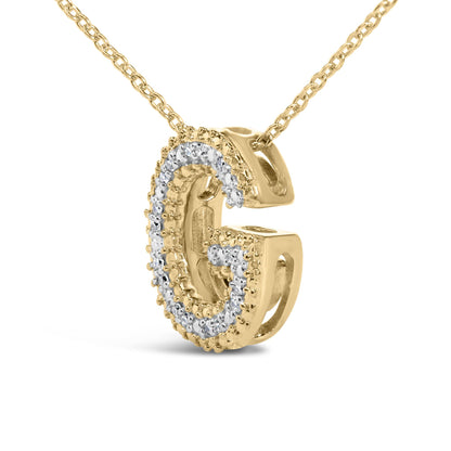 Close-up front angle of a yellow metal necklace pendant in the shape of the letter G, adorned with white round prong-set gemstones along the front surface, shown on a white background.