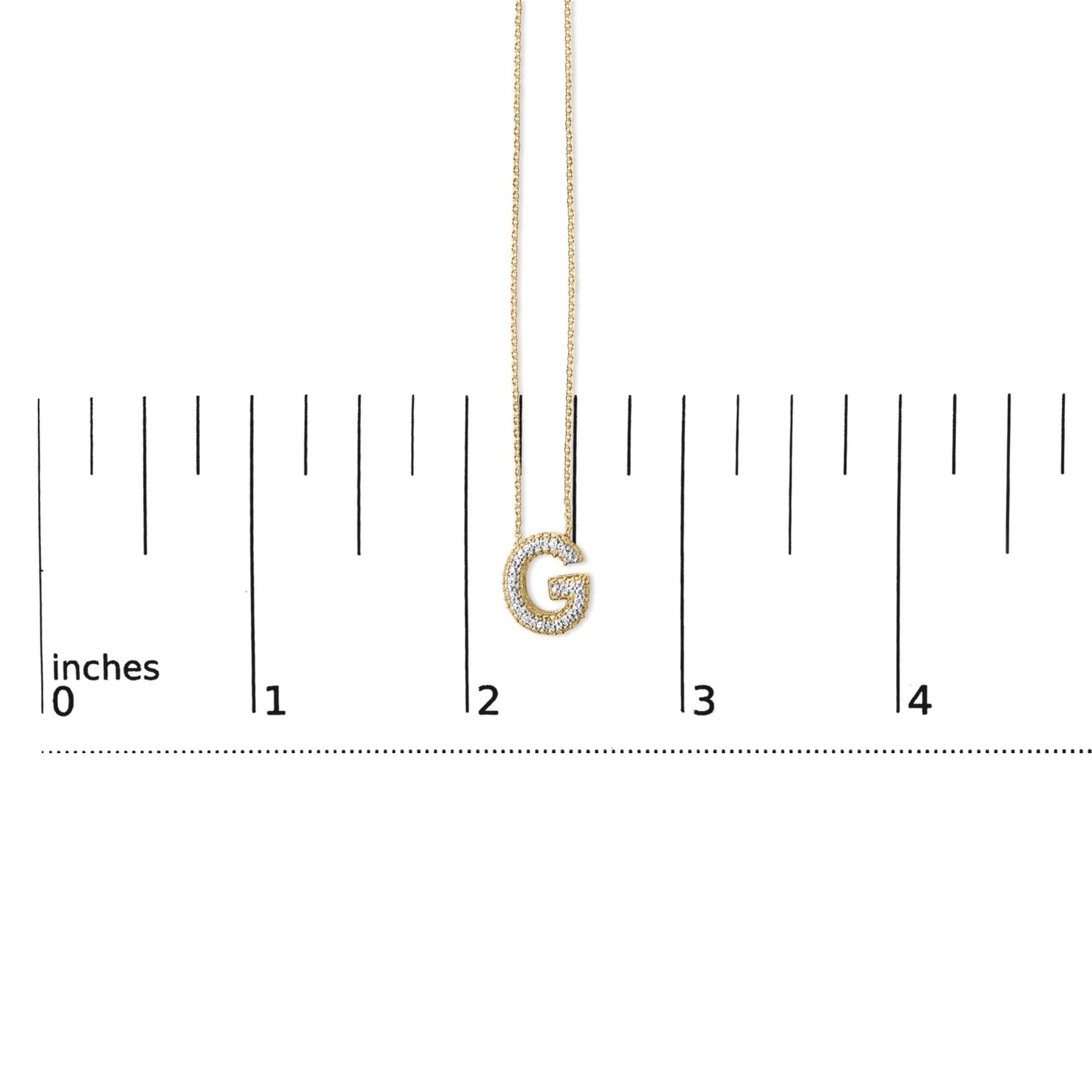 Yellow necklace with a pendant shaped like the letter G, outlined with white gemstones, shown hanging on a ruler scale, front angle.