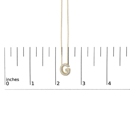 Yellow necklace with a pendant shaped like the letter G, outlined with white gemstones, shown hanging on a ruler scale, front angle.