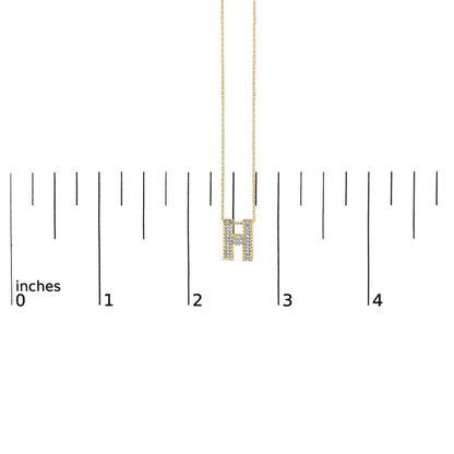 Yellow necklace with an H-shaped pendant adorned with round white gemstones in prong settings, shown on a scale, front view.