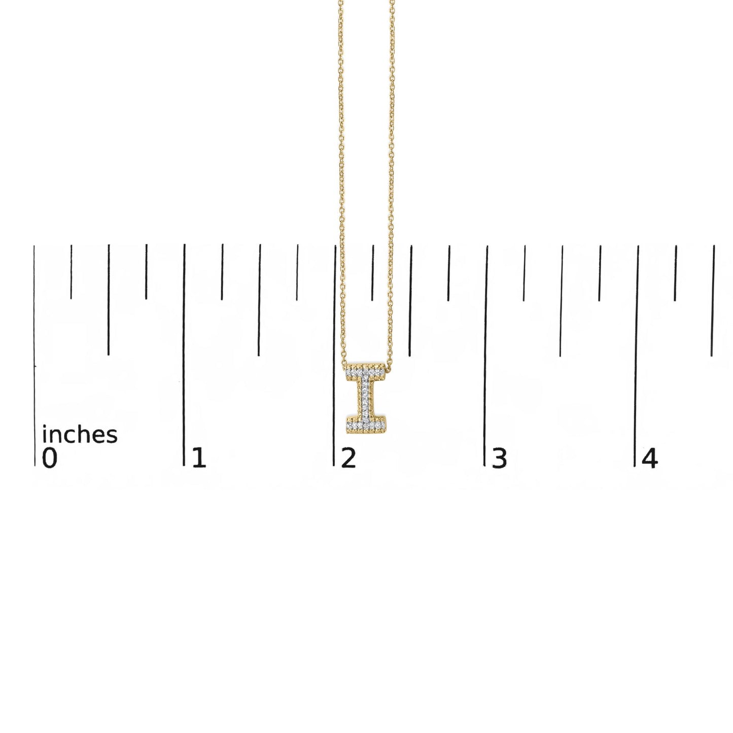 Close-up front view of a yellow metal necklace with a vertical bar pendant shaped like the letter 'I,' adorned with round white gemstones in a prong setting, shown on a scale with inch markings.