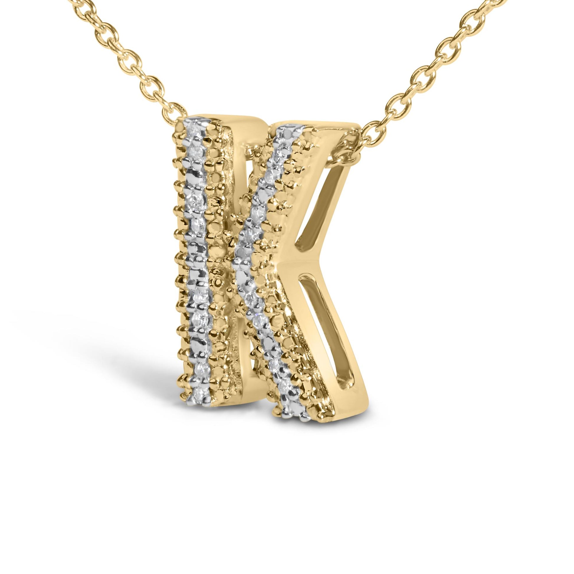 Close-up front view of a yellow metal necklace pendant shaped like the letter 'K,' featuring two rows of small white gemstones in prong settings running diagonally on the left side, shown on a white background.