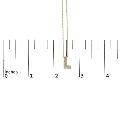 Close-up front view of a yellow metal necklace pendant in the shape of the letter 'L,' adorned with small round white gemstones in a prong setting, shown on a ruler scale.