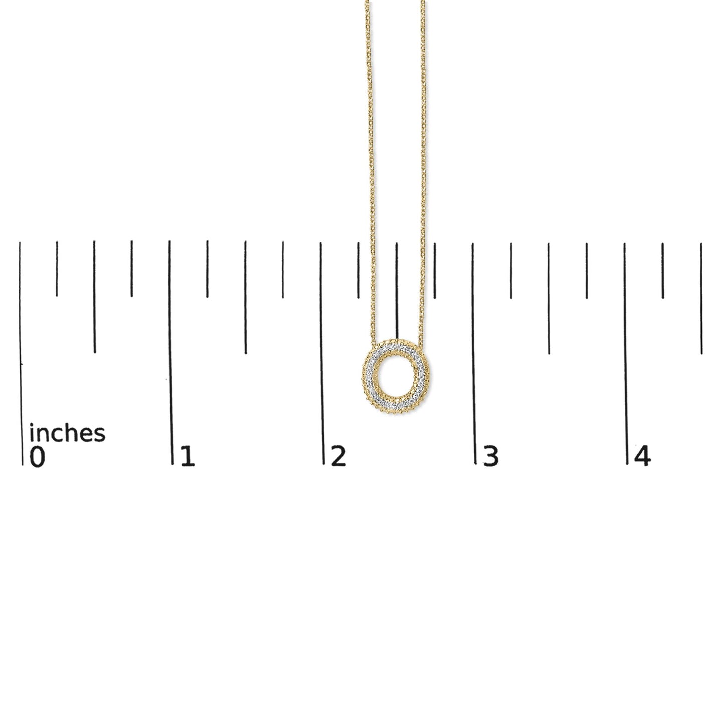 Yellow metal necklace with a circular pendant encrusted with white gemstones in a prong setting, shown from the front resting on a measuring scale.