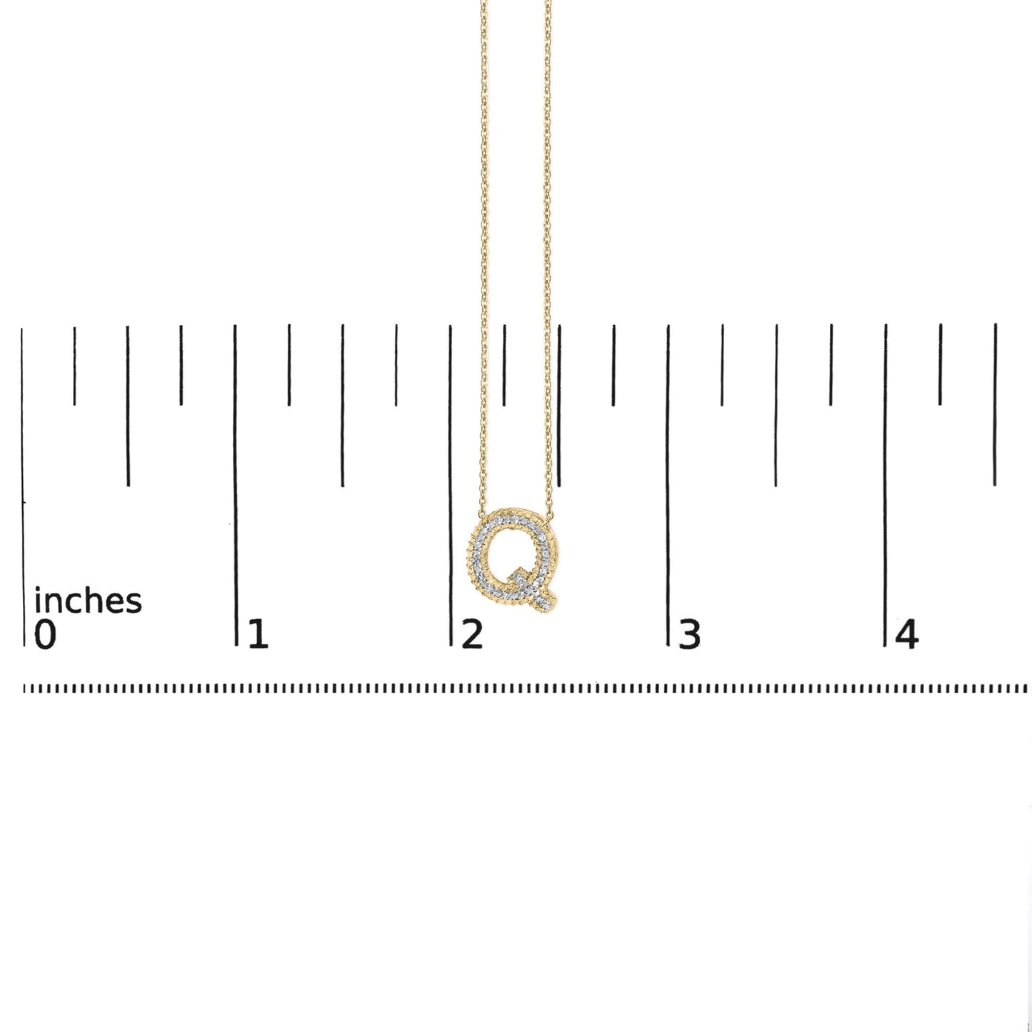 Close-up angled front view of a yellow metal necklace pendant in the shape of the letter Q, outlined with white gemstones in prong settings, shown on a ruler scale.