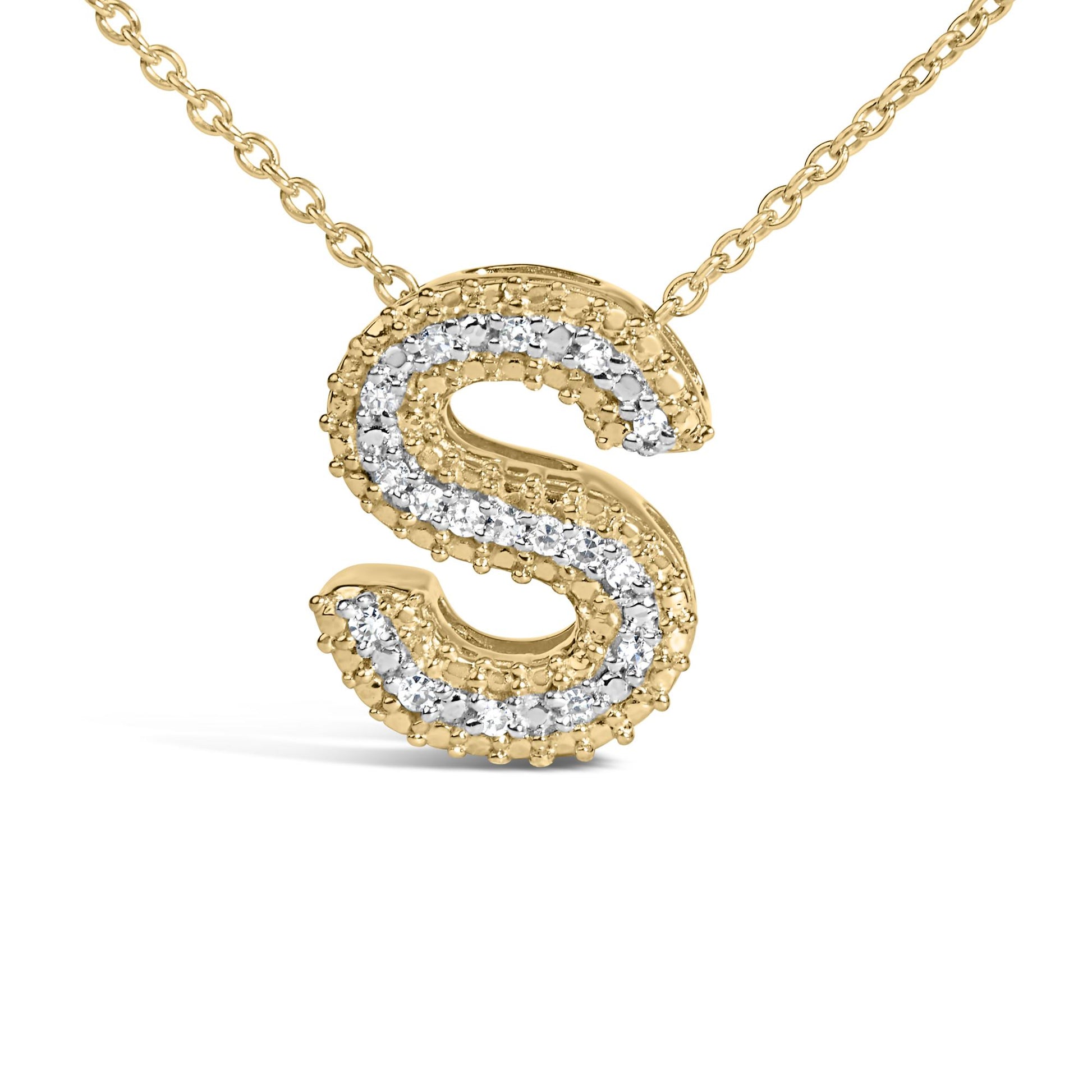 Close-up front view of a yellow metal necklace pendant in the shape of the letter 'S' accented with white round gemstones in prong settings.