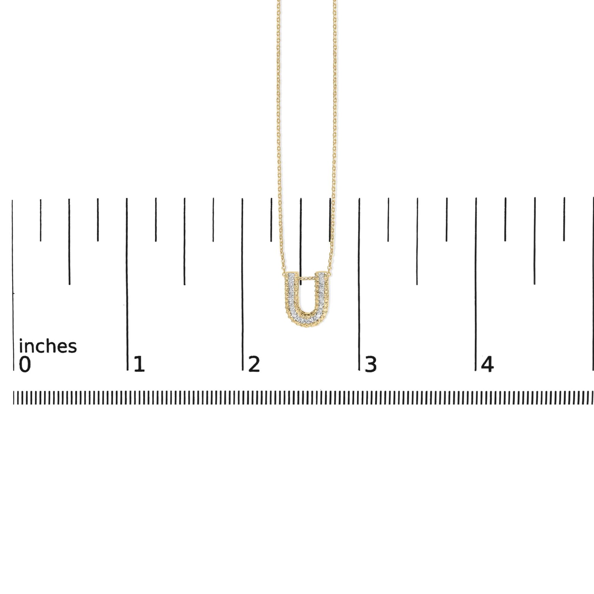 Yellow necklace with a U-shaped pendant adorned with white gemstones in a prong setting, shown on a scale from a front angle.