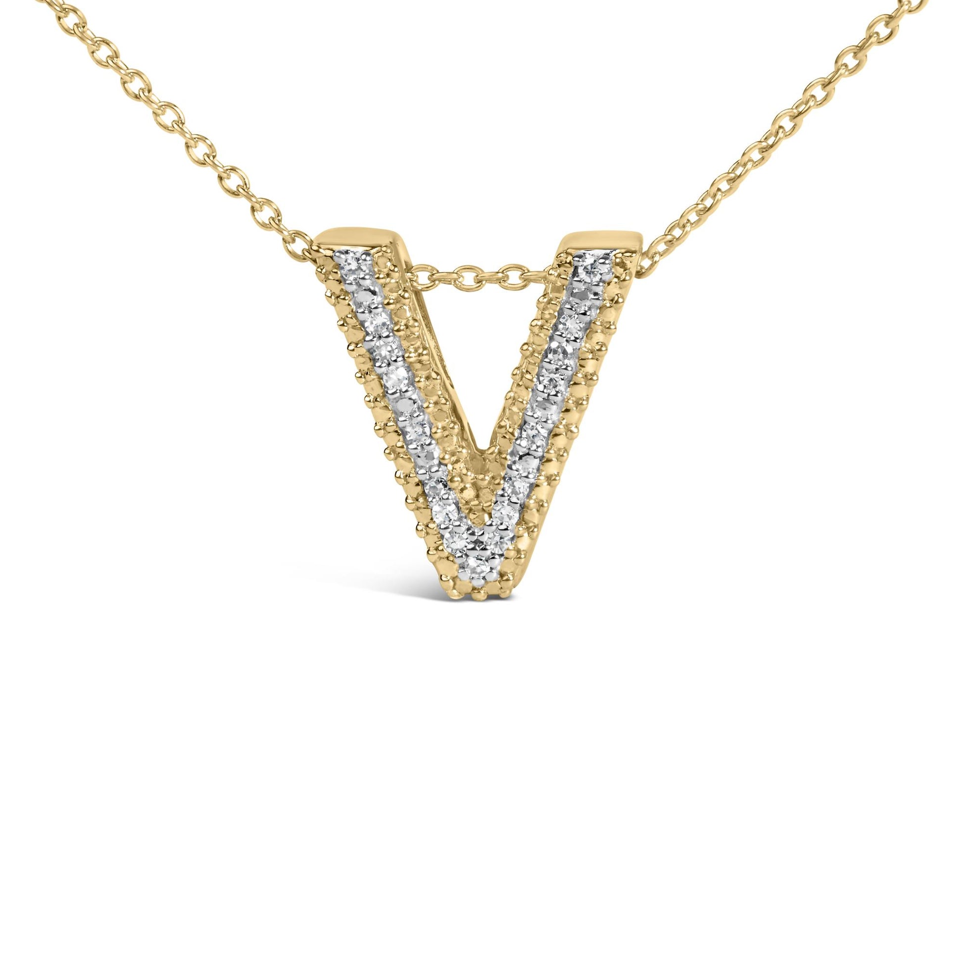 Close-up front angle of a yellow metal necklace pendant in the shape of a letter V, adorned with a row of white round gemstones set in prongs down the center.
