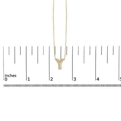 Yellow necklace with a Y-shaped pendant set with white gemstones, shown on a scale, front view.