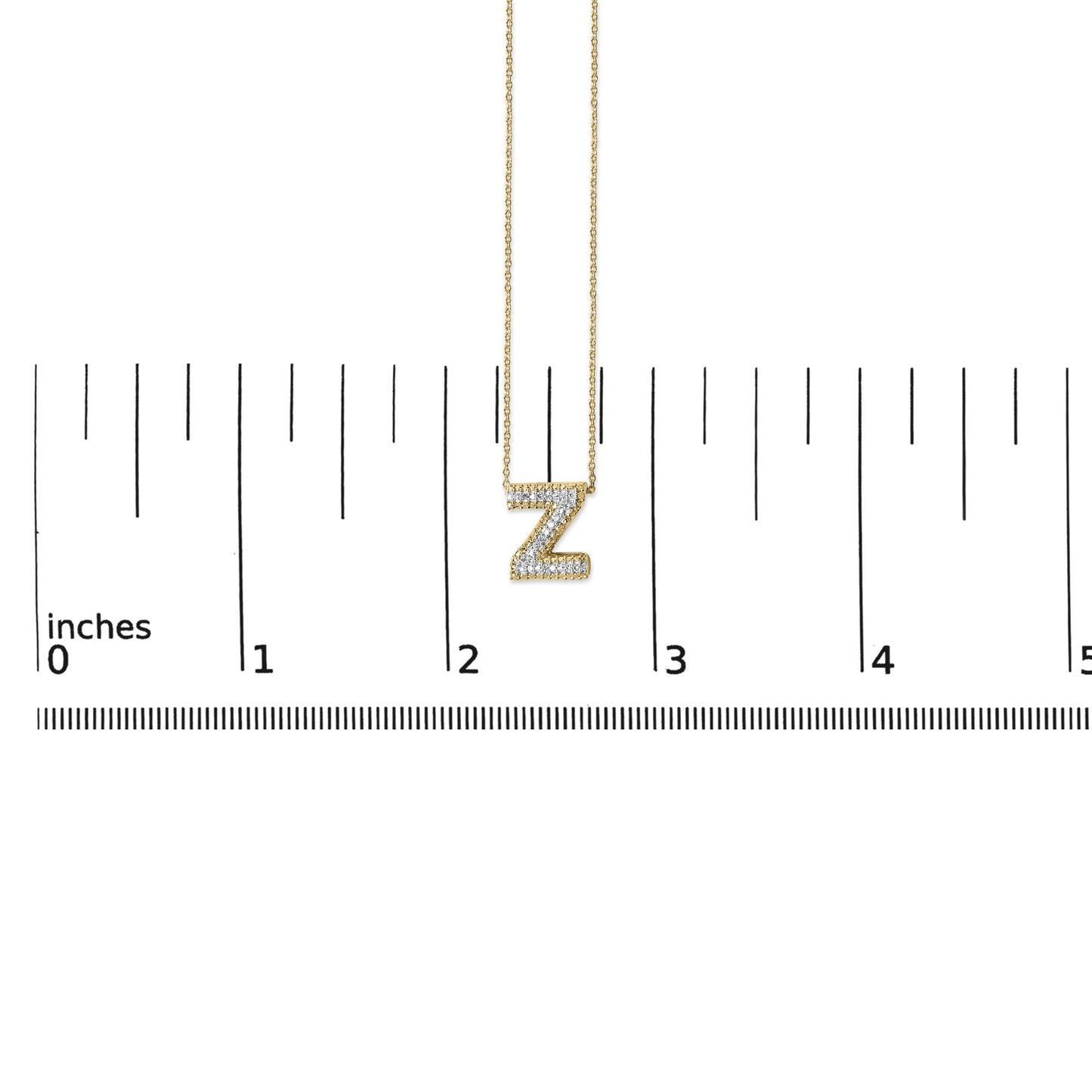 Yellow metal necklace with a 'Z' pendant encrusted with white gemstones in a prong setting, shown on a ruler scale from a front angle.