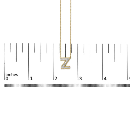 Yellow metal necklace with a 'Z' pendant encrusted with white gemstones in a prong setting, shown on a ruler scale from a front angle.