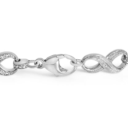 Close-up front angle of a white metal bracelet chain with some links featuring small round white gemstones in a pave setting.