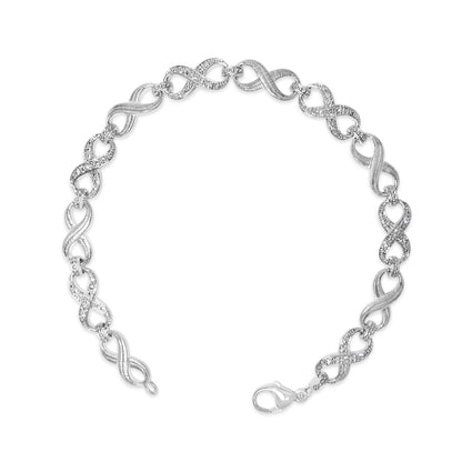 Top-down close-up image of a white metal bracelet with alternating plain and white gemstone pave infinity-shaped links, shown flat on a white background.