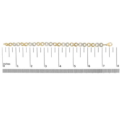 Yellow metal bracelet with alternating infinity shapes, some pave set with white round gemstones, shown flat on a ruler, top-down angle.