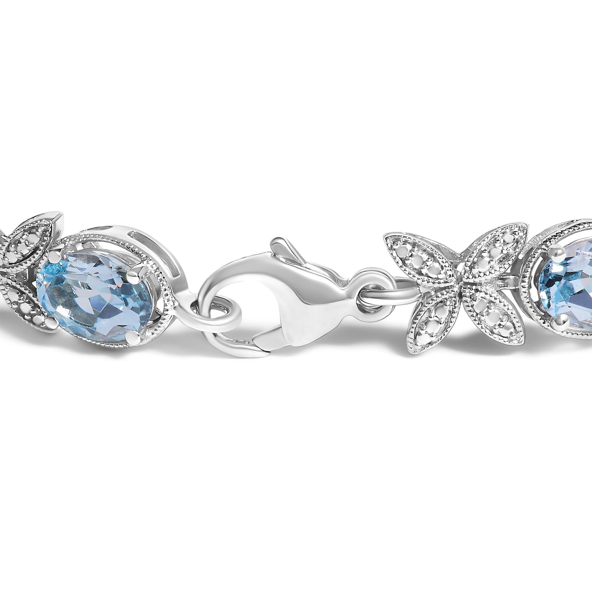 Close-up side angle of a white metal bracelet featuring oval blue gemstones with prong settings and butterfly-shaped links adorned with small round white gemstones in pave settings, showing the clasp.