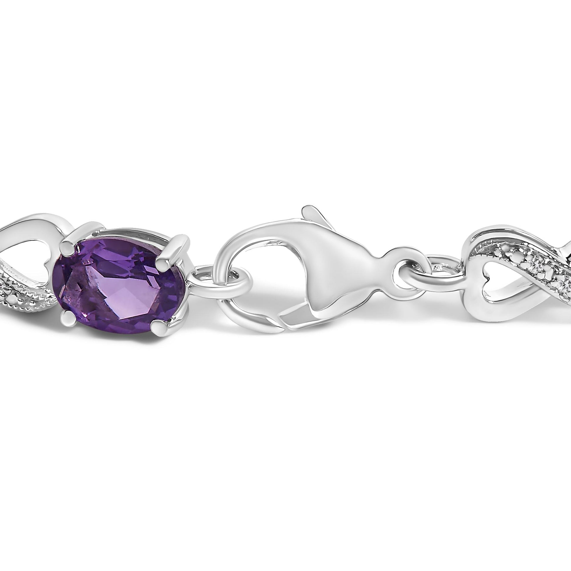 Close-up side angle of a white metal bracelet clasp featuring an oval purple gemstone in prong setting and adjacent white round gemstones with prong setting.