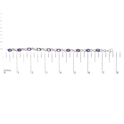 White metal bracelet with oval purple gemstones and round white gemstones in prong settings, displayed flat on a ruler for size reference, shown from top-down angle.