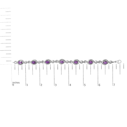 White bracelet with alternating oval purple gemstones and round white gemstones in prong settings, shown on a scale in a top-down view.