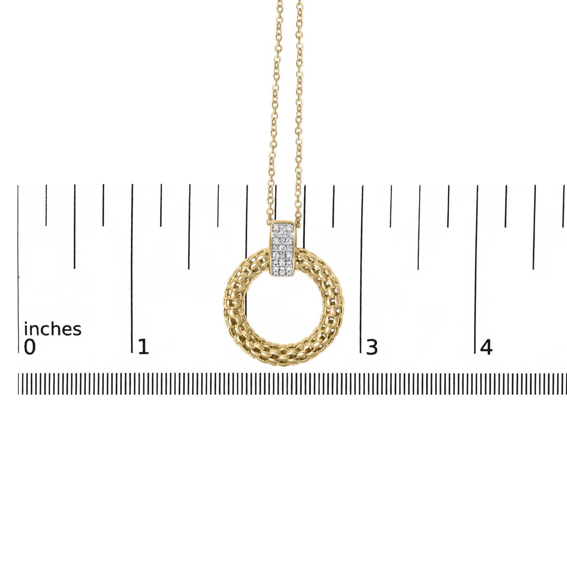 Front close-up of gold vermeil pendant showing braided circular ring and micro-pave diamond bar on inch ruler for scale