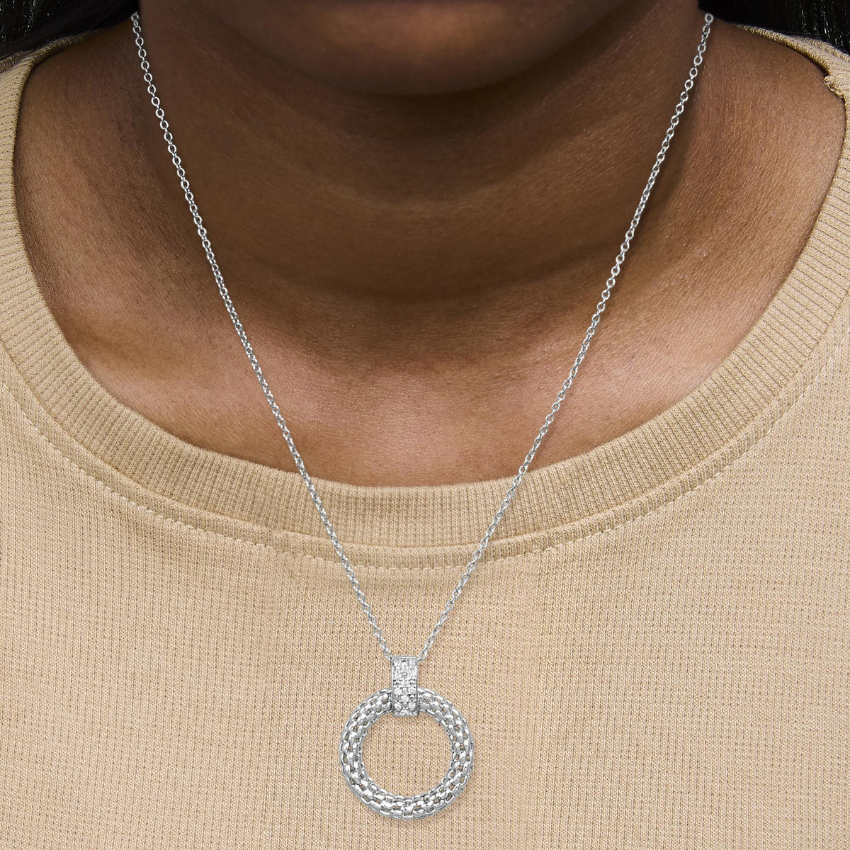 White metal necklace with a circular pendant featuring micro-pave white gemstones, shown worn on a model from the front angle.