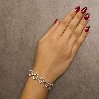 Bracelet with yellow and white metal featuring flower-shaped links with white gemstones in a pave setting, shown worn on a model's wrist, top-down angle.