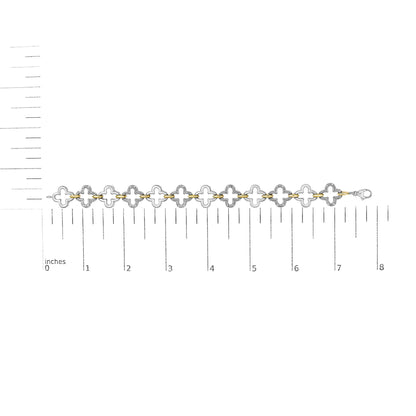 Bracelet with alternating yellow and white metal clover-shaped links, white gemstones in pave setting on white metal, shown flat on a scale from above.