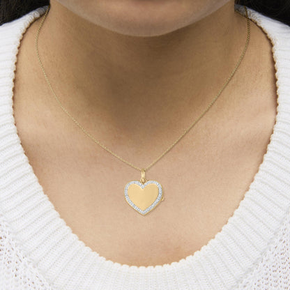 Close-up front view of a model wearing a yellow metal heart-shaped pendant necklace with a border of white gemstones in a pave setting.