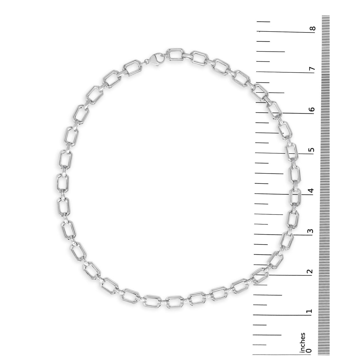 Top down shot of a white metal linked necklace with pave set white gemstones, shown on a scale.