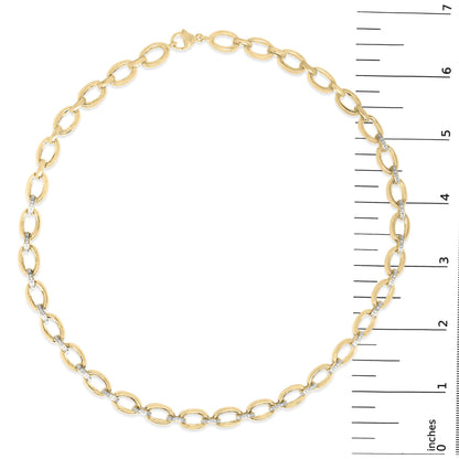 Yellow metal necklace with alternating plain oval links and oval links with pave-set white gemstones, shown on a scale, top view.
