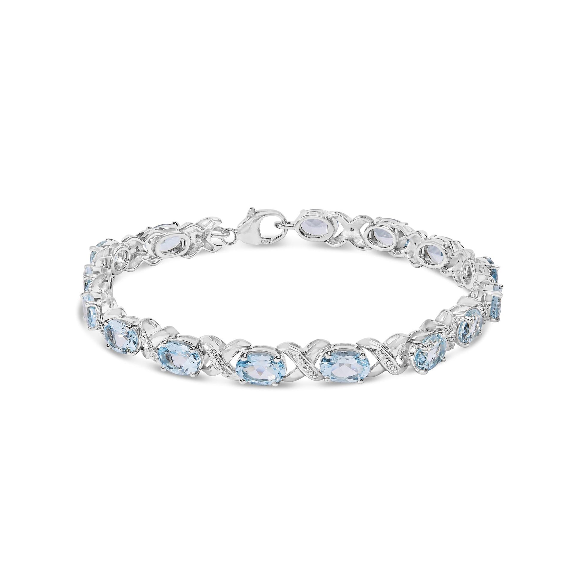 White metal bracelet with alternating oval blue gemstones and round white gemstones in prong settings, shown from a slightly elevated front angle.