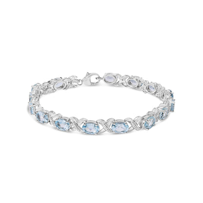 White metal bracelet with alternating oval blue gemstones and round white gemstones in prong settings, shown from a slightly elevated front angle.
