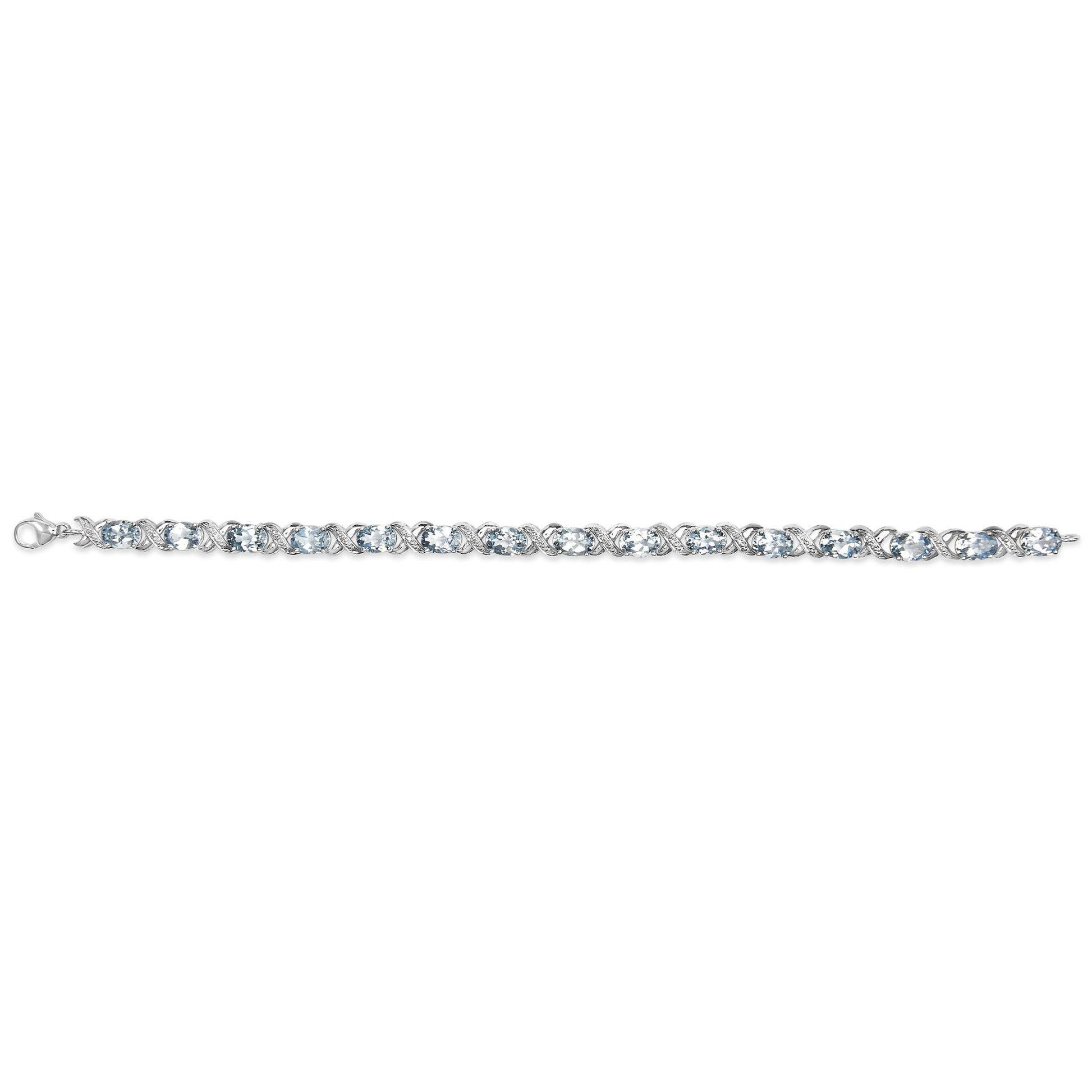 White metal bracelet with alternating oval blue gemstones and round white gemstones in prong settings, shown from a top-down angle.
