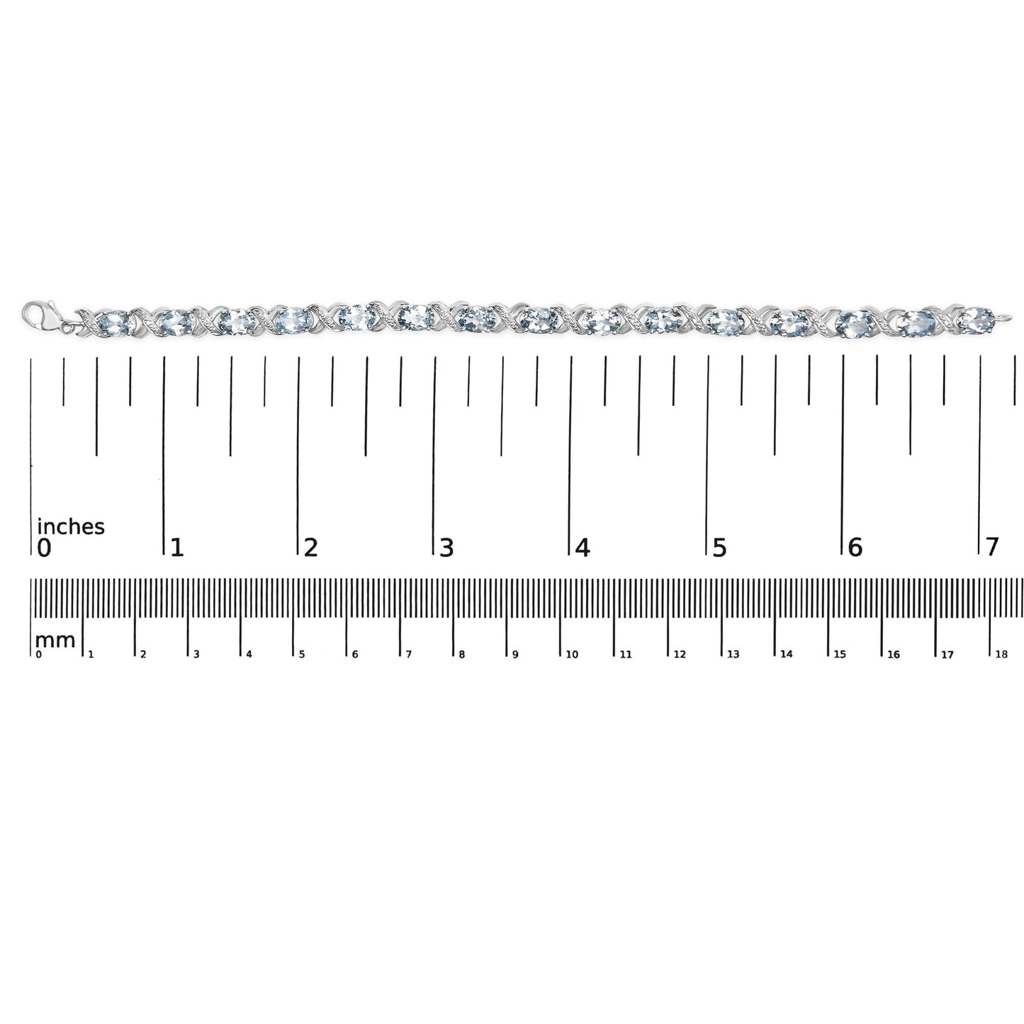 Top-down view of a white metal bracelet with alternating oval blue gemstones and round white gemstones in prong settings, placed on a ruler for size reference.