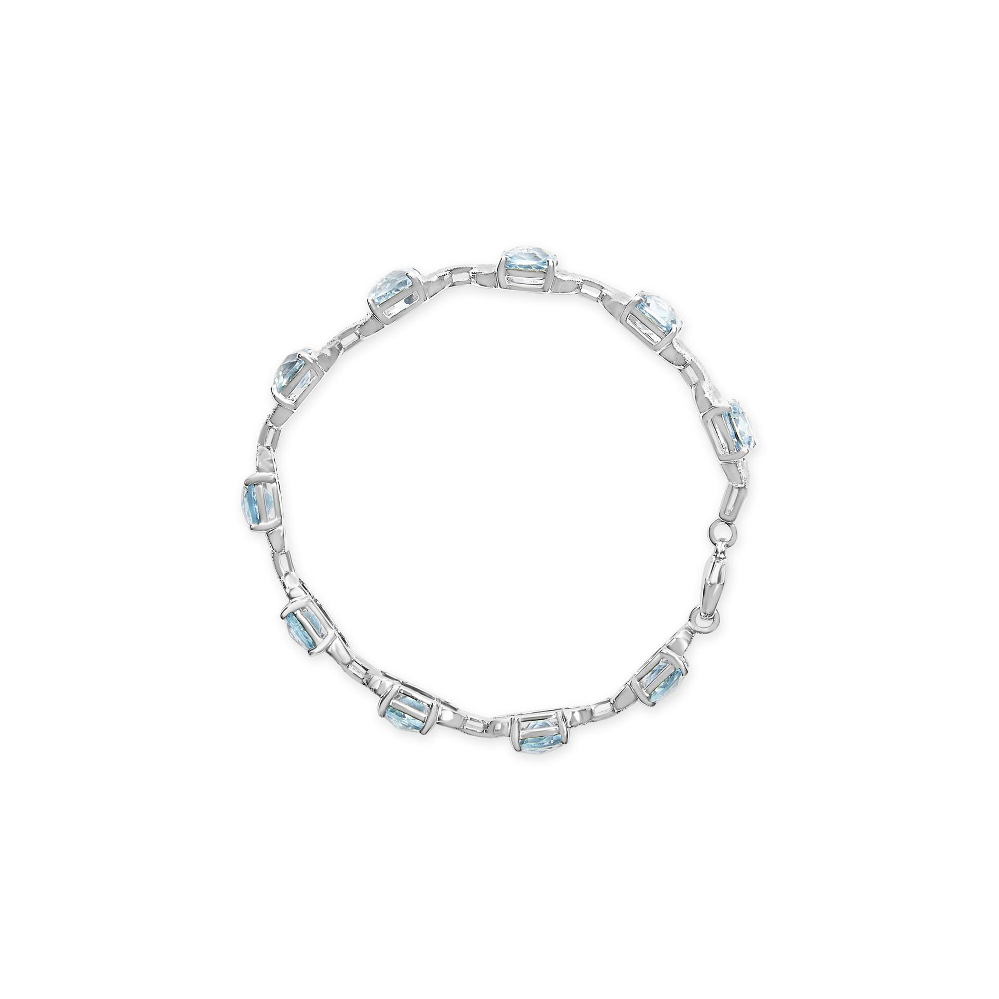 Top-down view of a white metal bracelet featuring alternating round white gemstones and cushion-shaped blue gemstones in prong settings.