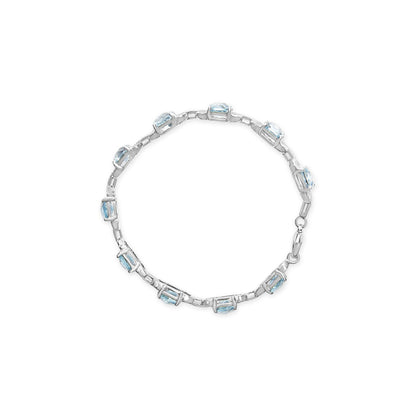 Top-down view of a white metal bracelet featuring alternating round white gemstones and cushion-shaped blue gemstones in prong settings.