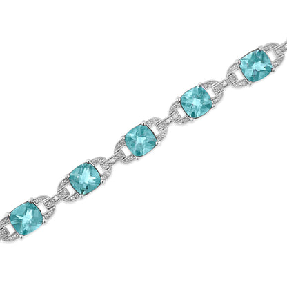 White metal bracelet with cushion-shaped blue gemstones and round white gemstones in prong settings, shown in a diagonal close-up view.