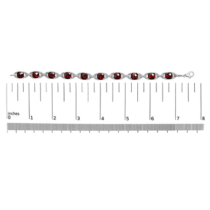 White metal bracelet with alternating round white gemstones and cushion-shaped red gemstones in prong settings, displayed flat on a ruler for size reference, top-down view.
