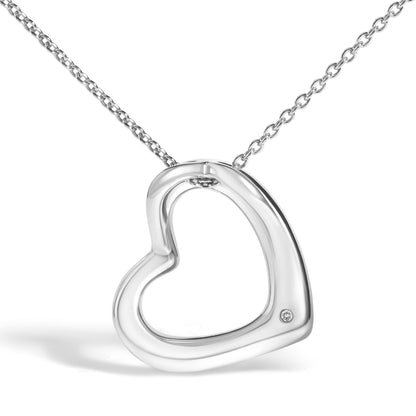 Close-up front angle of a white metal heart-shaped necklace pendant with a round white gemstone in bezel setting near the bottom, shown against a white background.