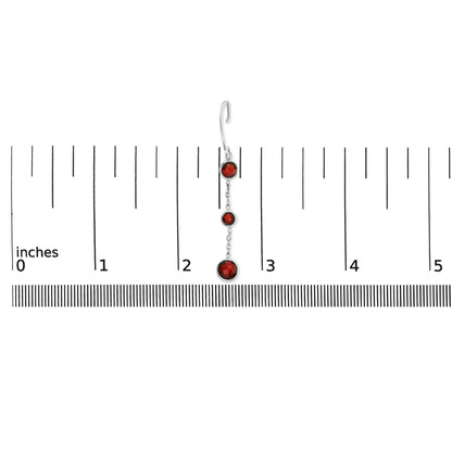 Single white metal earring with three round red gemstones in bezel settings, shown on a ruler for scale, photographed from the front.